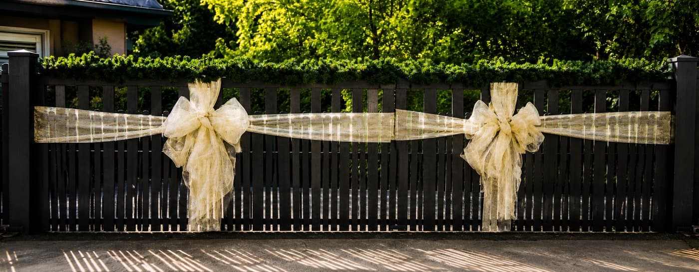 Two gold bows along a fence line with garland